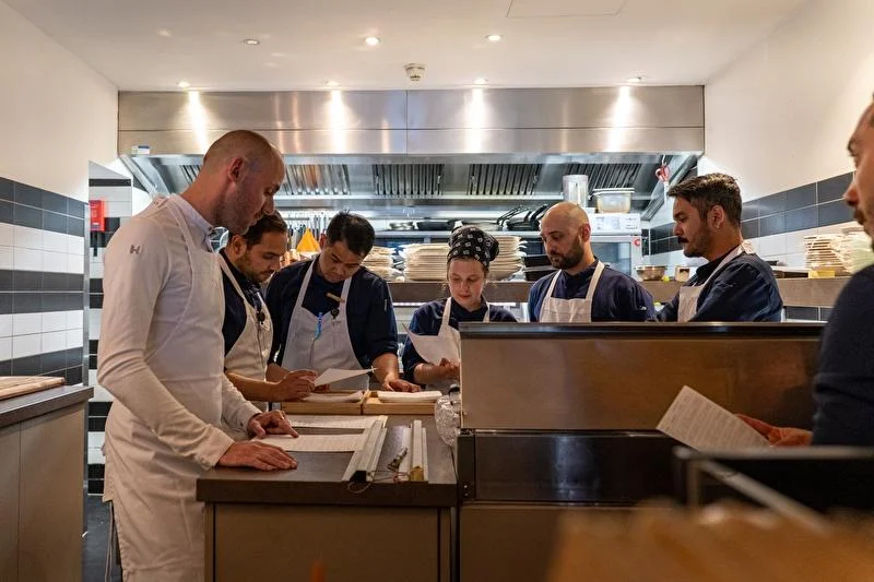 Restaurant kitchen team reviewing procedures together to maintain consistent operations